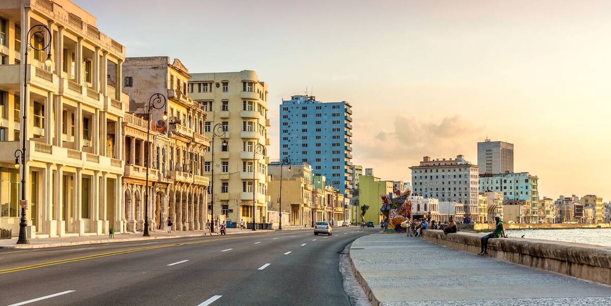 El Malecón de La Habana al atardecer, con los edificios del paseo marítimo iluminados por el sol bajo.